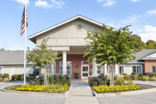 A white house with a red brick facade and a flag on the front lawn. AI generated content